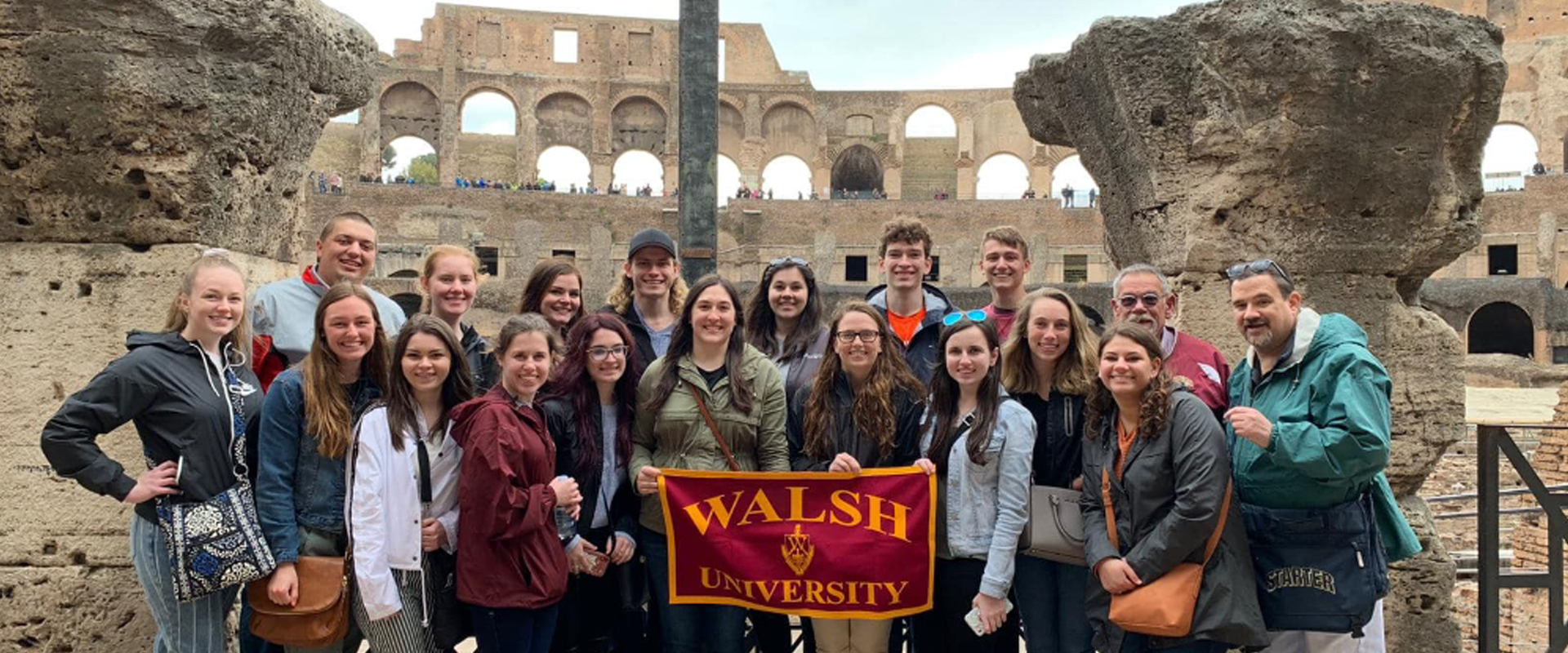 Walsh University Global Learning group in Rome holding up a Walsh flag