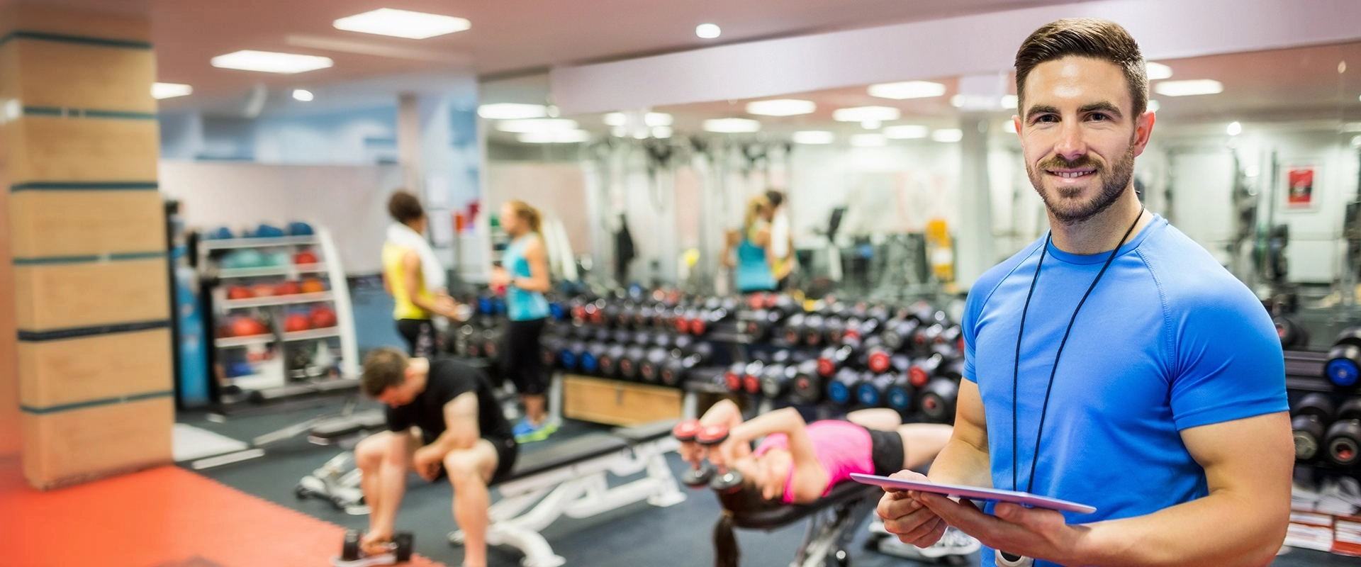 photo of a male trainer standing in a busy gym